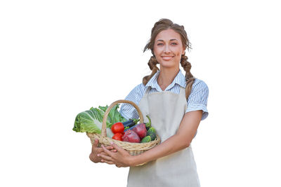 Portrait of smiling young woman holding apple against white background