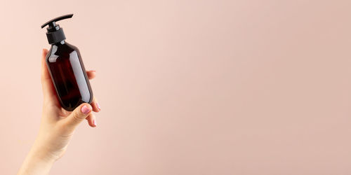 Mockup of a brown dispenser with a natural cosmetic product in a female hand 