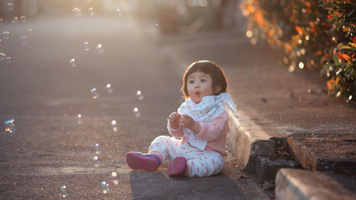Full length of cute girl sitting on land
