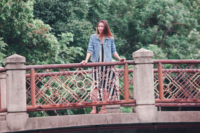 Portrait of young woman standing on footbridge