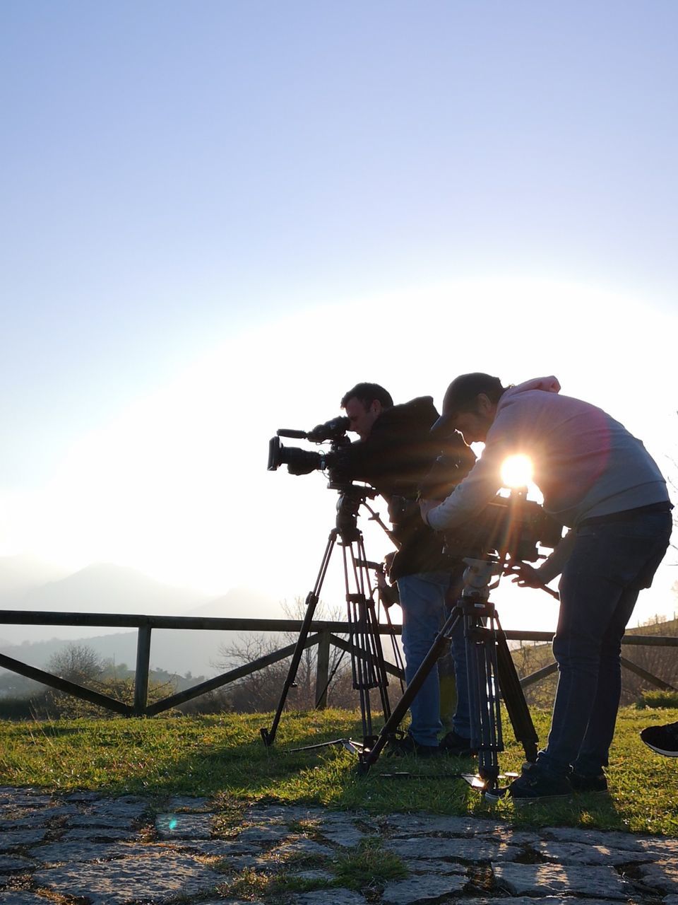 sky, men, real people, sunlight, nature, clear sky, bicycle, transportation, lifestyles, people, full length, two people, photography themes, day, sunbeam, tripod, activity, leisure activity, outdoors, camera - photographic equipment, photographer, lens flare