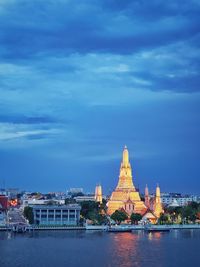 View of temple by river against sky in city