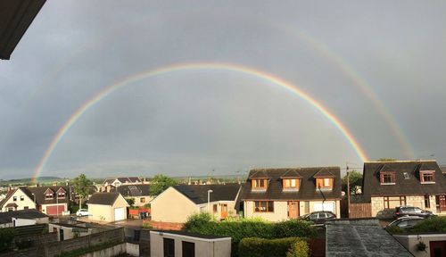 Rainbow over buildings in city against sky
