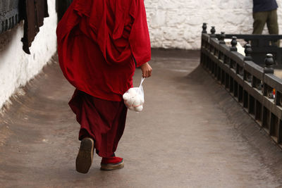 Low section of monk holding food on footpath