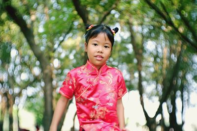 Portrait of smiling girl sitting against trees