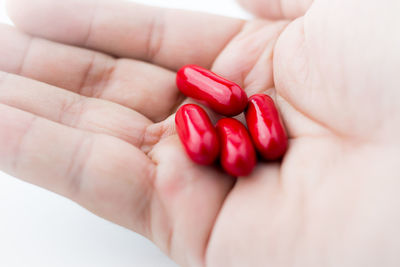 Close-up of hand holding red capsules 