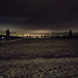 Scenic view of field by city against sky at dusk