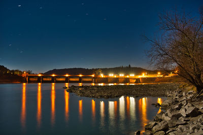 Reflection of illuminated trees in lake against sky at night
