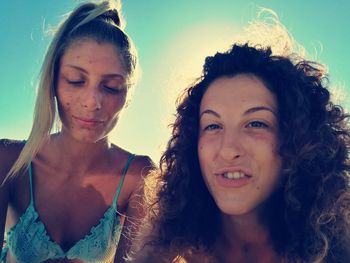 Portrait of young woman with friend at beach on sunny day