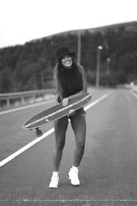 Portrait of young woman skateboarding on road