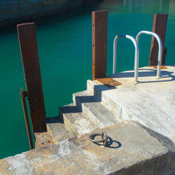 Ladder and bollard at port over sea