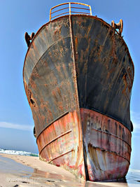 Abandoned boat moored on beach against sky