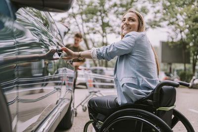 Happy disabled woman opening car door