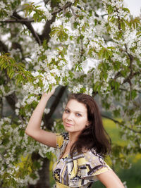 Portrait of young woman standing by tree