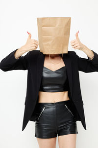 Woman covering face with bag gesturing while standing against white background