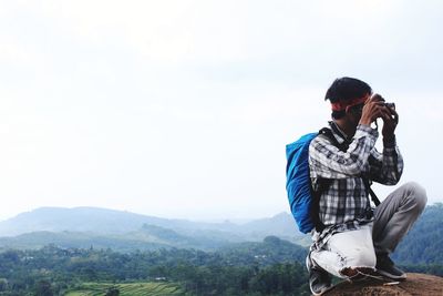 Man photographing on mountain against sky