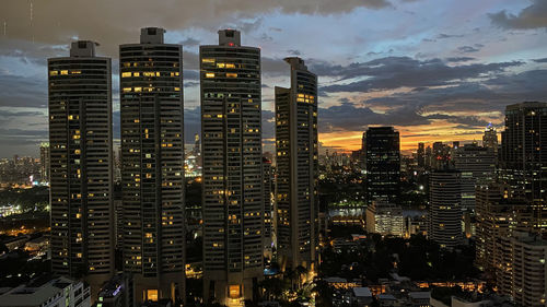 Illuminated buildings in bangkok city against sky at sunset