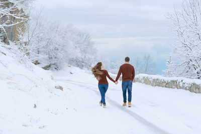 Rear view of friends walking on snow covered landscape