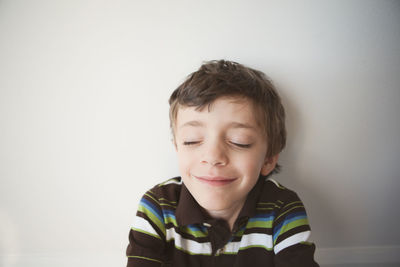 Boy with eyes closed against white background