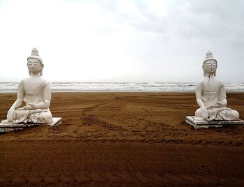 Statue by sea against sky