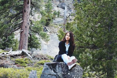 Young woman sitting on rock in forest