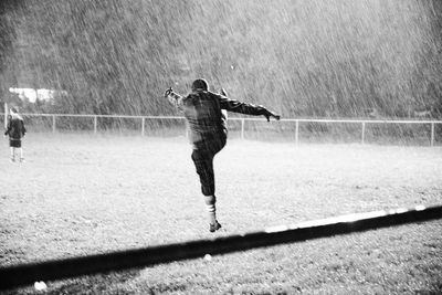 Man kicking over field during rainy season