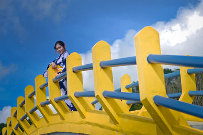 Low angle view of woman on yellow playground against sky