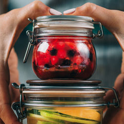 Woman holding jars with fermented fruits.