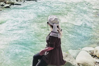 Woman sitting on rock by river