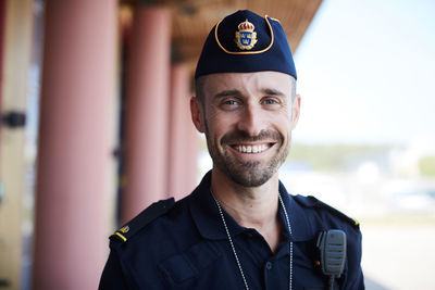 Portrait of smiling policeman standing outside police station