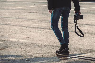 Low section of man with camera waking on footpath