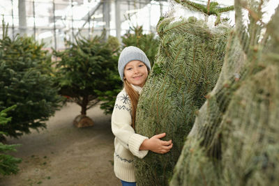 A girl chooses a christmas tree in a shop