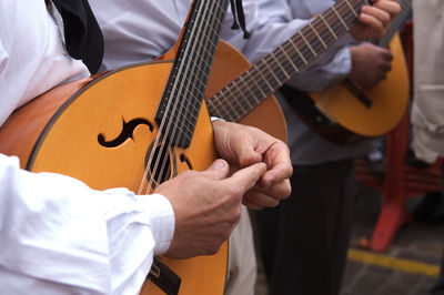 Midsection of musicians playing on street in city