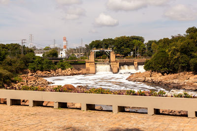 Arch bridge over river against cloudy sky