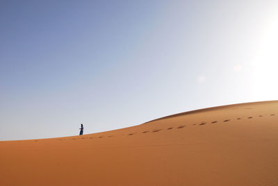 Low angle view of person on sand dune against sky
