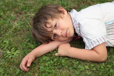 Portrait of cute boy lying on grass outdoors