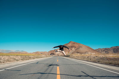 Road sign on desert against clear blue sky