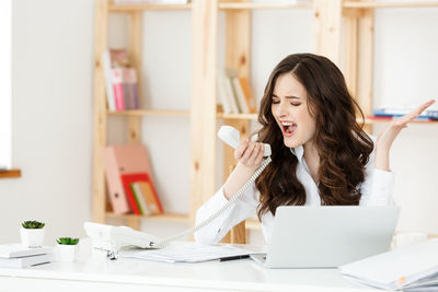 Frustrated businesswoman talking on phone at office