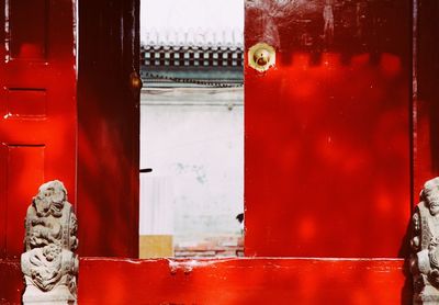 Close-up of statue against red door