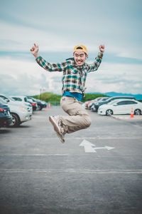 Happy man jumping in parking lot against sky