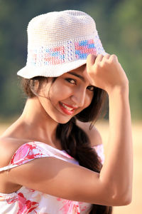 Portrait of smiling woman wearing hat while standing on field