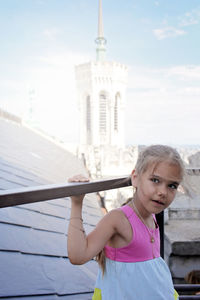 Portrait of girl standing against built structure