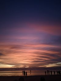 Silhouette people at beach against sky during sunset