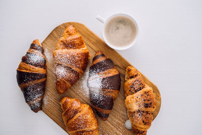 Cup of coffee and a bunch of appetizing brown and chocolate croissants with powdered sugar