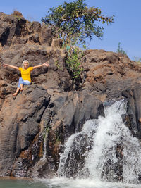 Rear view of woman standing by waterfall