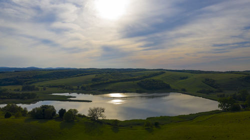 Scenic view of landscape and lake against sky during sunset