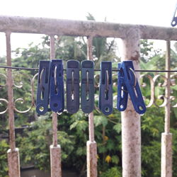 Close-up of clothes hanging on metal fence against blue sky
