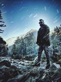 Man standing on rock against sky