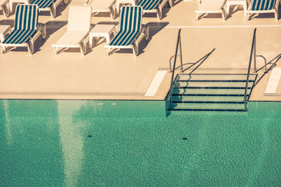 High angle view of empty chairs by swimming pool