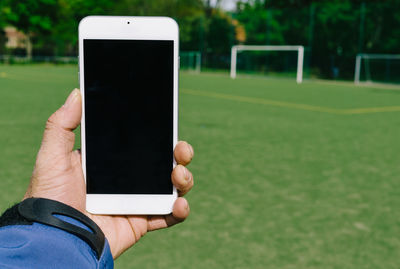 Midsection of person holding mobile phone in park